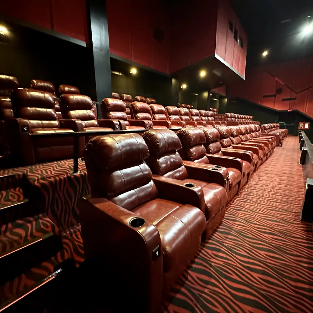 Rows of red leather recliners on a red zebra carpet at The Galaxy Cinema